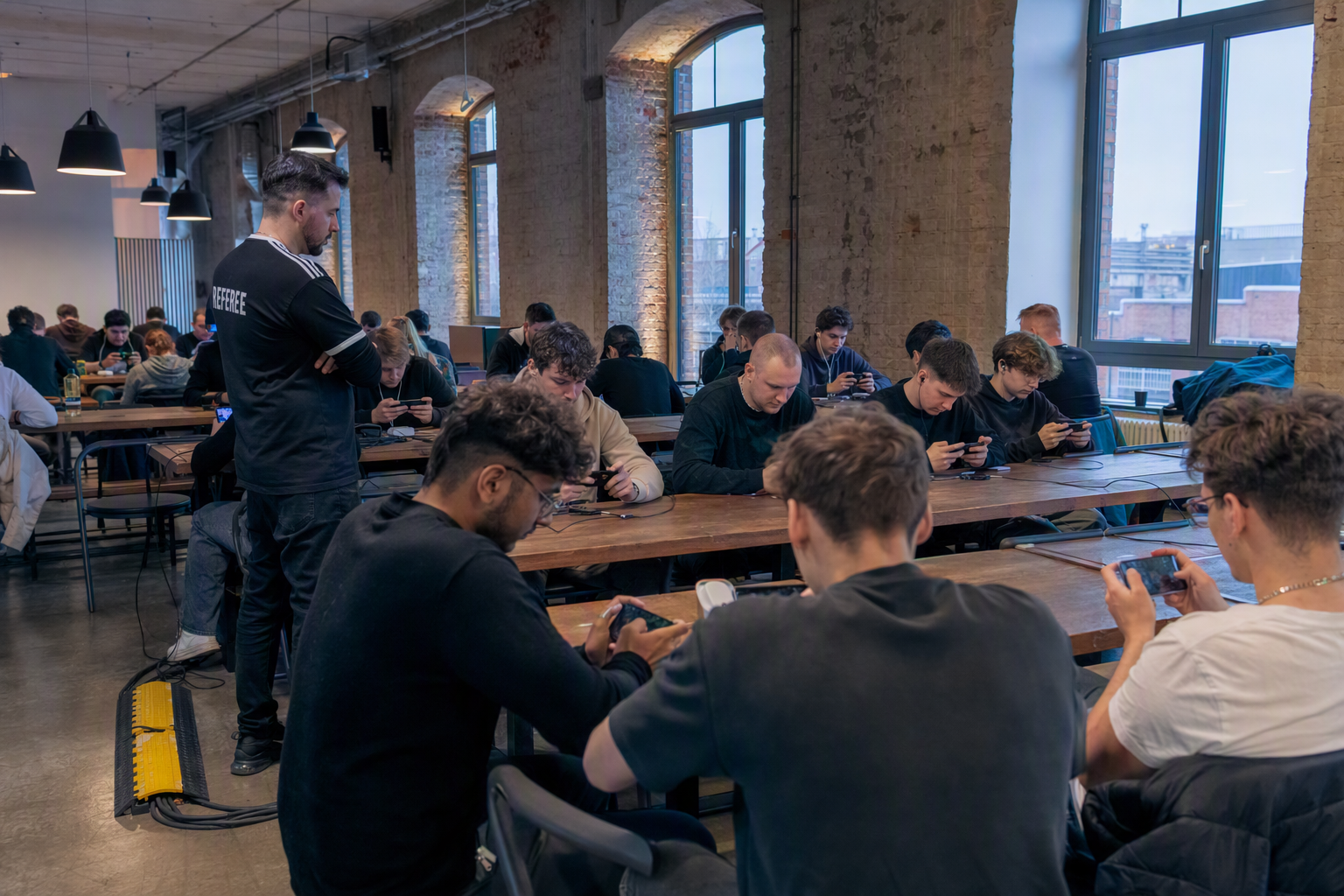 Players using phones under neutral stage lighting at a Berlin community esports venue